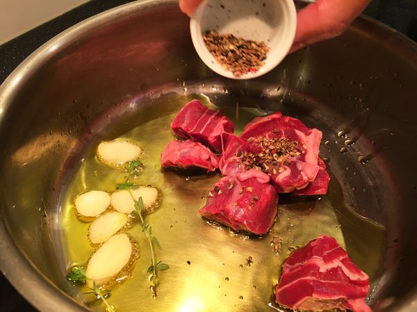 取鍋熱油，將蒜頭百里香附入爆香後，加入牛腱、黑胡椒粒炒香。