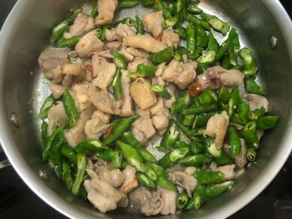 加入辣椒後進行翻炒，再加入已切好的糯米椒，將雞丁與糯米椒風味融合，炒至糯米椒表面軟化。