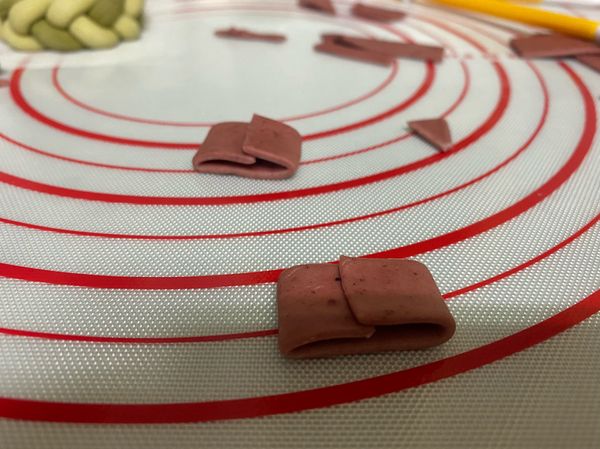 用20g麵糰揉上紅麴
擀薄切成長四公分寬ㄧ公分
如圖對內摺用水黏上
中間壓扁