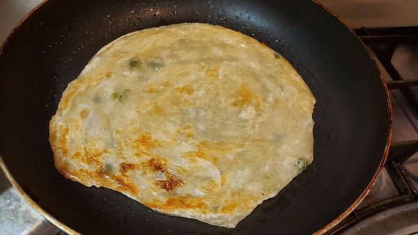 用噴油瓶在鍋裡噴點油，將蔥油餅放進去，二面都煎熟
最後打一顆蛋