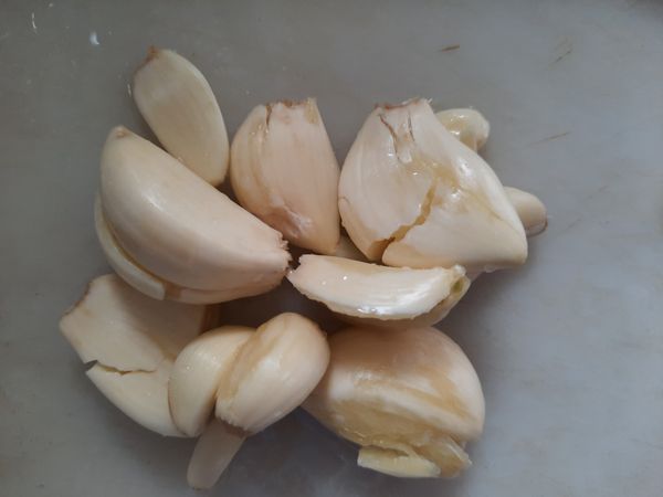 蒜頭用刀子拍扁，撥開皮清洗乾淨。