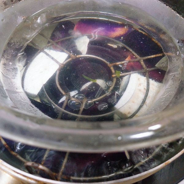 另外煮鍋熱水,水滾後將茄子放入,並在表面壓上重物讓茄子完全浸泡在熱開水中.（茄子完全浸泡水中這樣煮出來的茄子顏色較漂亮不易轉黑）.