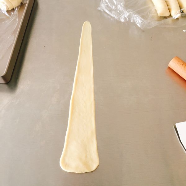 整型：擀成上窄下寬的橢圓形面片，從一側卷起來，卷成上細下粗的長條錐狀，捏緊連接，再擀成長條，長度約30-33cm。