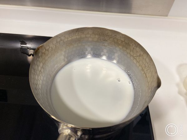 先將一半鮮奶加糖煮至微熱，熄火。加入餘下鮮奶降溫。