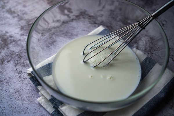 玻璃碗裡倒入砂糖，煉奶和全脂牛奶。慢慢攪拌，不用大力打發。可以感受到沒有沙沙的可以了；