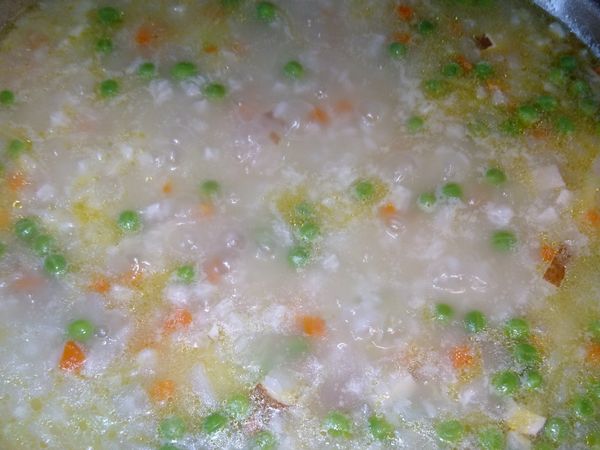 炒出香味後加水大火燒開，放入白米，青豆，豆乾高麗菜絲大火煮滾約5分鐘，再轉中小火慢燉。中間要多攪拌幾次才不會糊鍋。30分鐘左右，臘八粥就煮好了。起鍋前2分鐘放入青蒜苗稍煮調味即可。