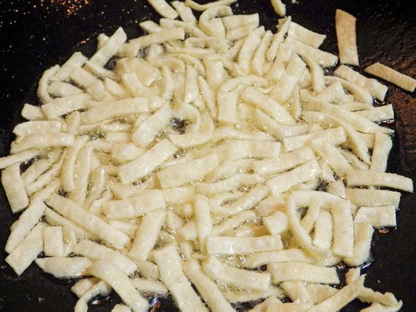 把餃子皮分批入鍋油炸，變炸邊攪拌…
餃皮切勿一次全部放入，鍋裡過於擁擠會讓餃皮無法伸展澎脹會導致餃皮不酥脆