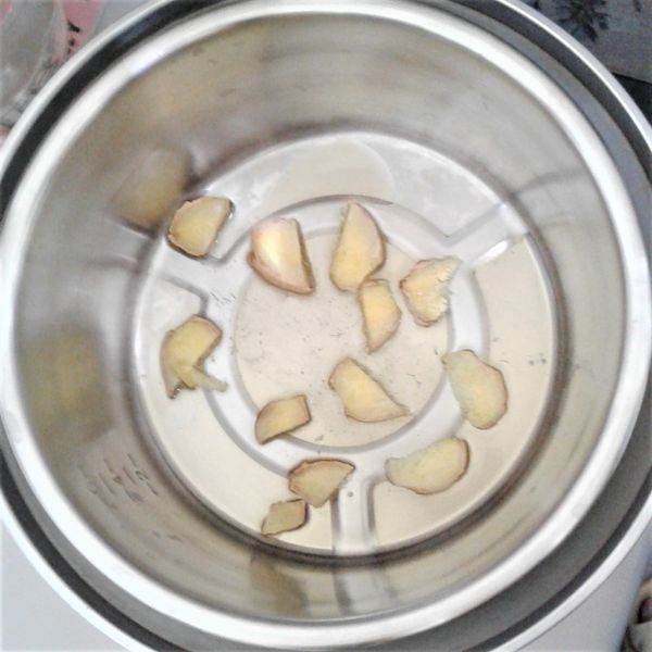 電鍋外鍋放入蒸盤，加入2刻度量米杯的水，然後將內鍋放入，在內鍋裡鋪上10片老薑片，並均勻淋上2湯匙芝麻油，按下開關，煮約3分鐘跳起，等候降溫(約10分鐘)。