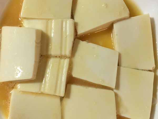 一顆雞蛋加半小匙鹽打散，嫩豆腐瀝除水份切片裹上蛋液⋯