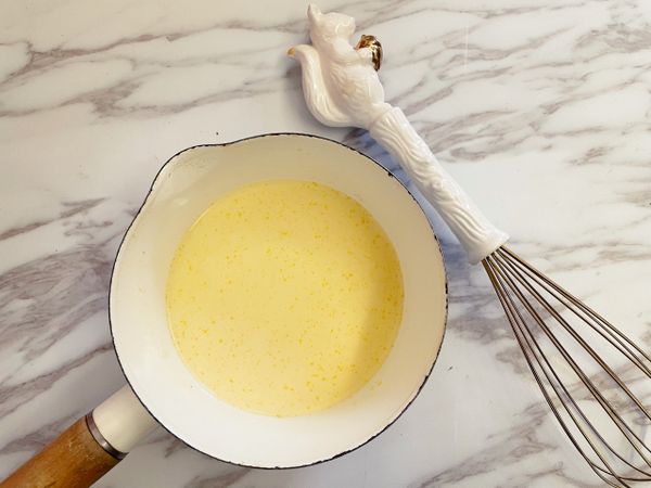 接著將布丁粉、蛋黃及牛奶倒入鍋中拌勻，以中火加熱至沸騰後轉小火煮一分鐘、過程中要不停地攪拌。