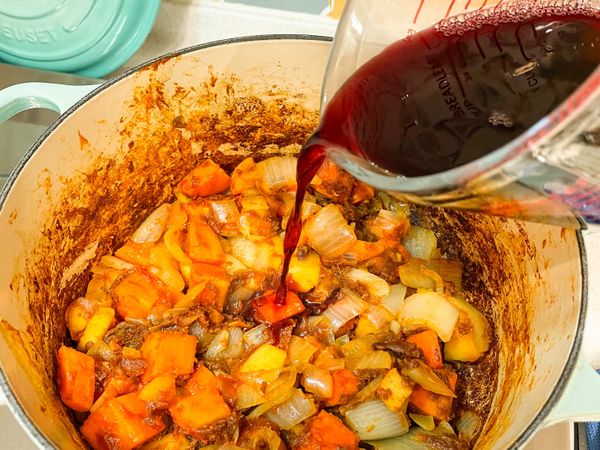 加入紅酒及水，努力攪拌，把鍋底的風味都刮起來一起燉煮