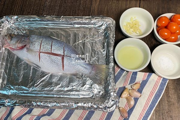 烤盤舖上錫箔紙，放入鱸魚，整尾魚身和魚肚內抹上橄欖油、鹽、蒜泥。