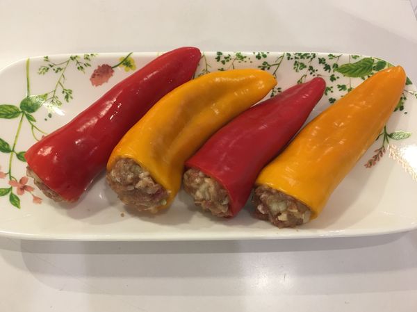 將調味好的內餡，均勻鑲入甜椒中。
再將甜椒放置烘烤鍋，表面噴上少許油。