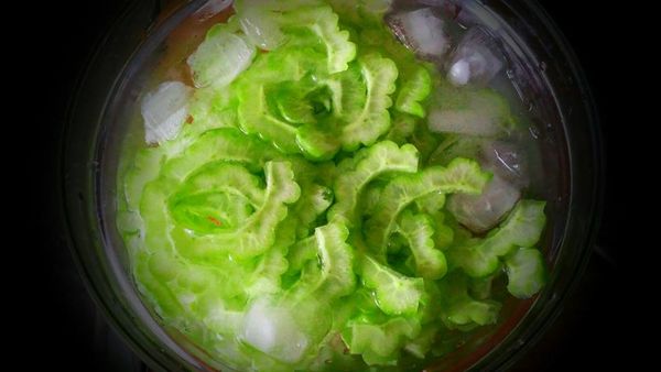 苦瓜洗淨，用湯匙刮下薄膜、去籽切成薄片。 

經沖水約5~10分鐘後，準備冰開水及冰塊，將苦瓜浸泡冰水中。