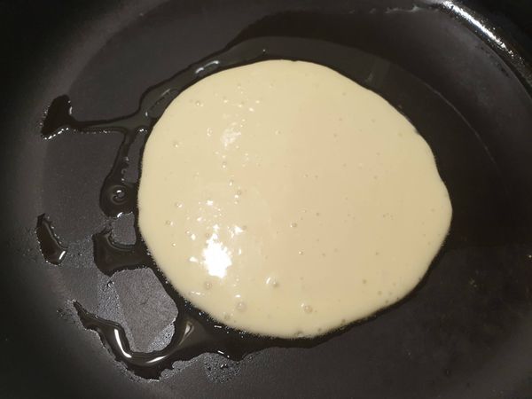 起一個鍋，放一點油，用一大湯匙舀麵糊倒入鍋內，從中間開始倒，麵糊會自己擴散開來成為圓形。