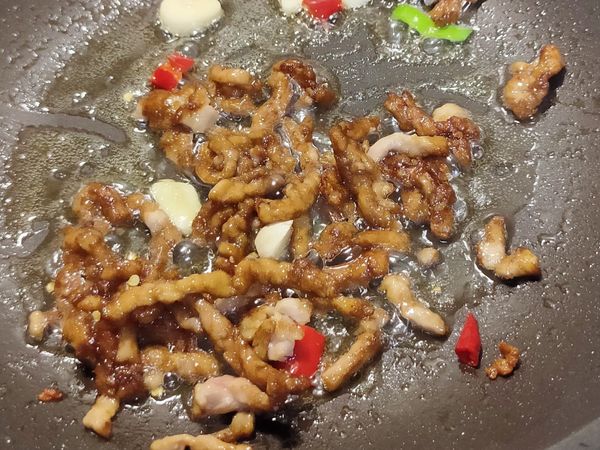 起油鍋，爆香蒜片/辣椒，炒熟肉絲。