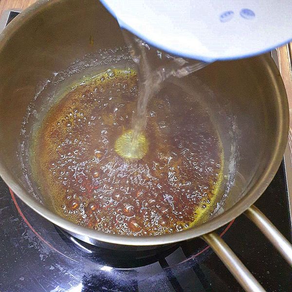 開小火將糖煮到融化，會變成焦糖色並散發出焦糖的香氣，熄火後分次將水加到焦糖液中，分次加入是為了要避免焦糖太濃稠而快速硬化，加水降溫時要小心避免被濺出的焦糖燙傷。