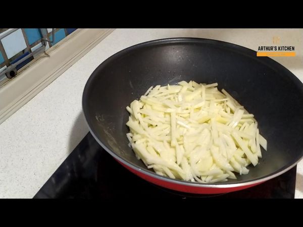 將馬鈴薯鋪在平底鍋上，用小火煎至一面焦黃後翻面
