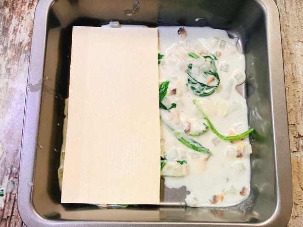 1、烤盤，底層先舖上一層白醬，再放上一層麵