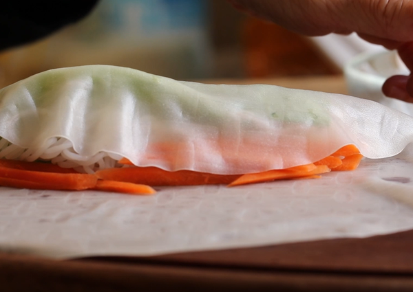 先將米皮捲一半，再左右往內折。