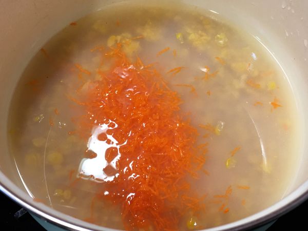玉米醬倒入湯鍋中，利用玉米醬的罐頭當量杯，兌上1.5杯的水(若喜歡較稀口感的可以將水量調至2杯)，加入紅蘿蔔絲，開火煮滾