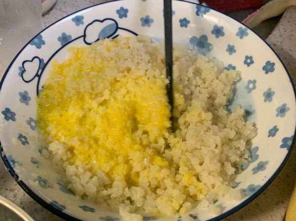 👧🏻打蛋，把兩顆蛋黃撈到花椰菜米中，拌勻備用