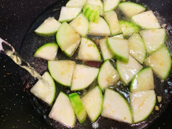 放入絲瓜拌炒，上色後加入開水