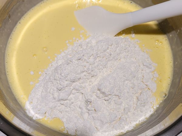 在已拌勻的乳酪雞蛋糊中，加入過篩的低筋麵粉及玉米粉，以切拌的方式拌勻，不可過度攪拌，會導致出筋。