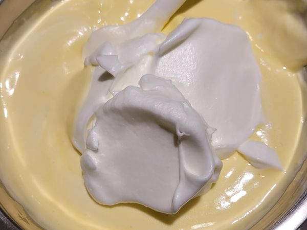 將蛋白霜分3次加入蛋黃糊中，以切拌方式拌勻，動作要輕，以免消泡。