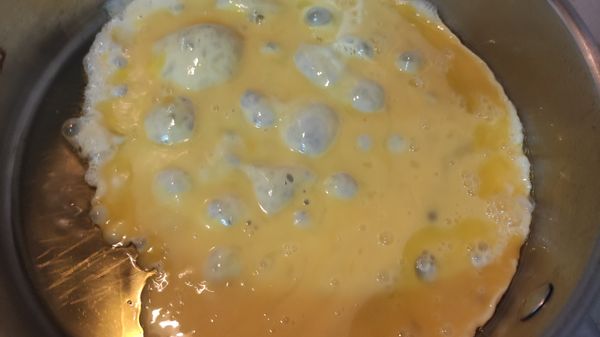 打三顆蛋花，倒入平底鍋中加熱，用鍋鏟將蛋攪散。