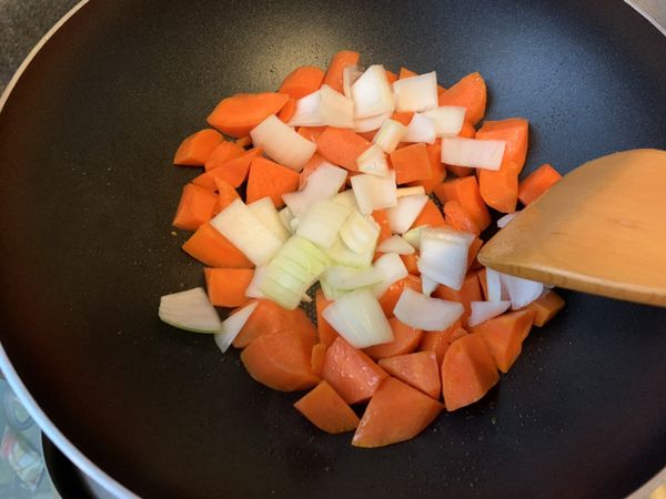 鍋內的油與紅蘿蔔充分融合後，下洋蔥拌炒。