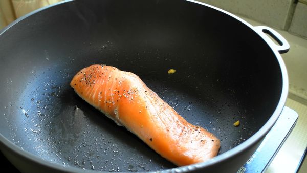 鮭魚魚皮面朝下放入鍋中，魚皮開始脆化後翻面，蓋上蓋子悶五分鐘