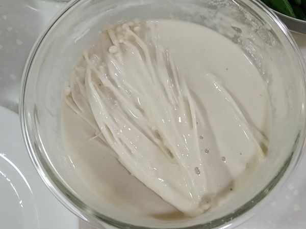 先將金針菇放入麵糊中，沾滿麵糊，以免等等手忙腳亂。