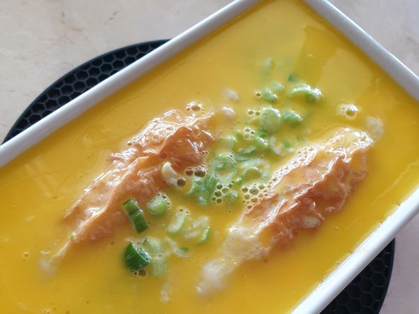 將容器從電鍋取出，倒入蛋黃液。