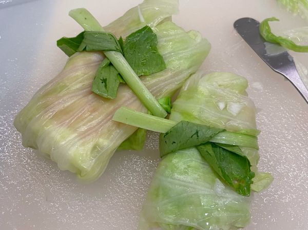 將內餡捏成長型或方型(視高麗菜葉大小決定)，上下>左右包起來，可重複疊加多片葉子，然後用青江菜葉子綑起來