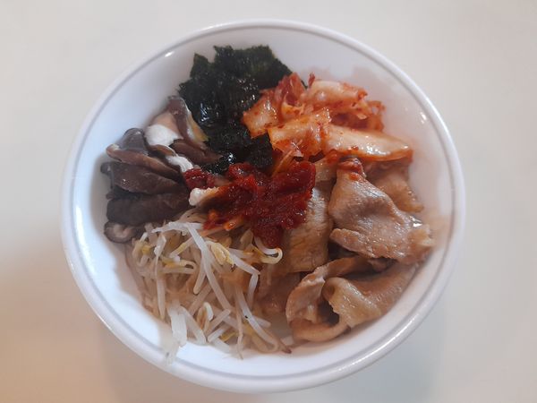將豆芽菜、香菇、豬肉片、撕碎的海苔、韓式泡菜依序放在白飯上，並加一大匙韓式辣醬。