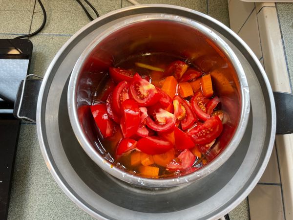 將炒好的料倒入電鍋內鍋，放入番茄、紅蘿蔔後，加水蓋過食材(照片尚未加滿水)後，外鍋倒入2.5米杯的水即可開蒸