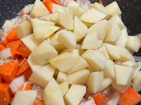 倒入紅蘿蔔、馬鈴薯，拌炒均勻。