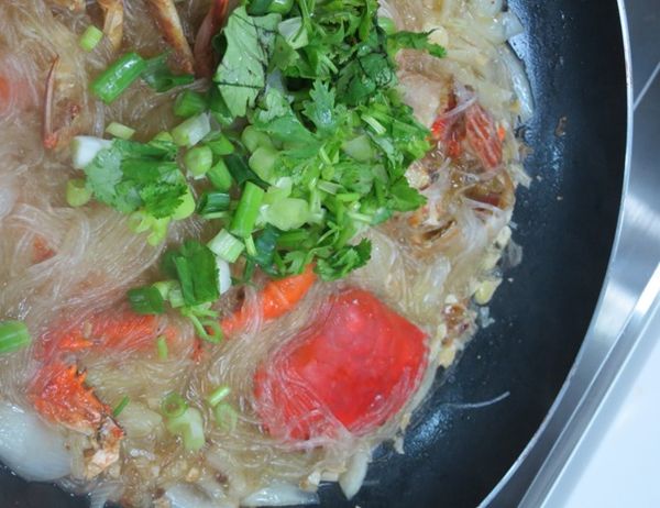 掀起鍋蓋灑上蔥末和芫荽末