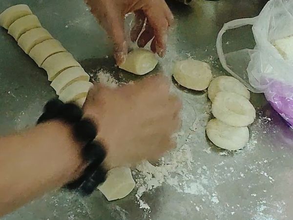 切好後底下鋪上麵粉，並且開始把麵團一個一個壓成圓片（大概就好）