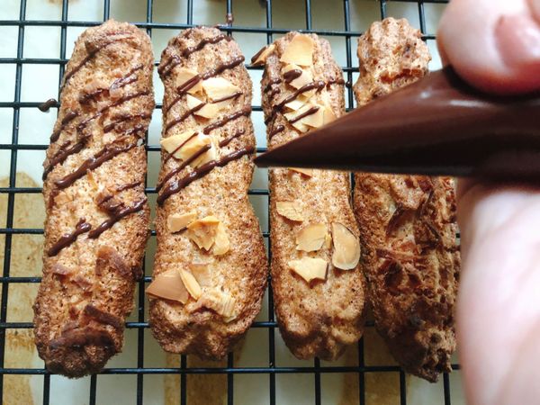 巧克力以隔水加熱或微波方式融化成巧克力液，裝入擠花袋後剪一個小洞，隨意擠在冷卻的杏仁餅乾表面