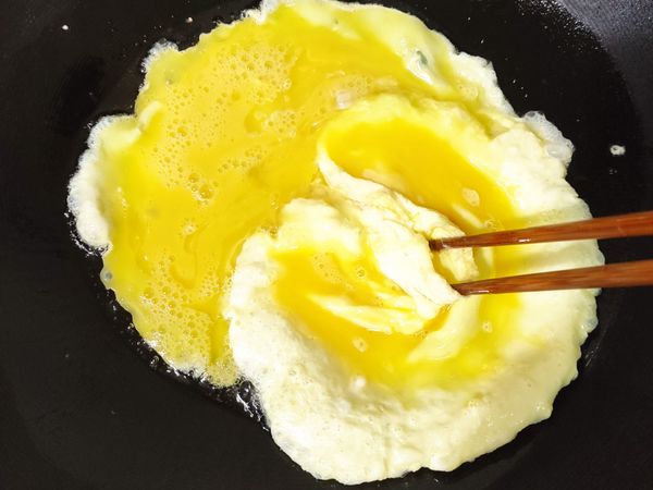 開中大火熱油先來炒蛋，記得油一定要熱，中大火把蛋放下去同時，可以用筷子繞圈加快熟透