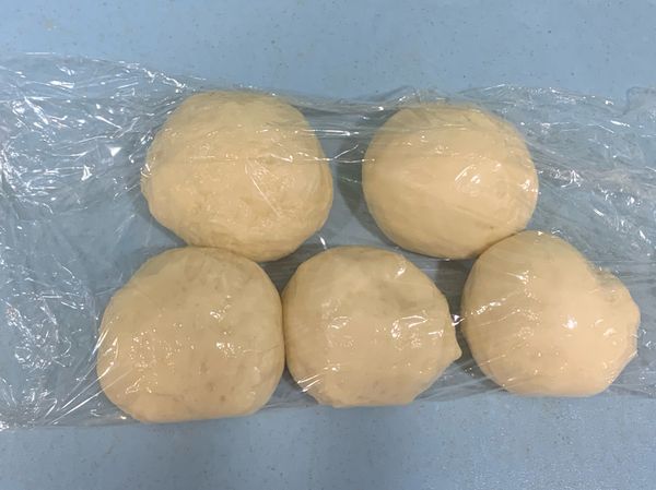 取出麵糰後，重新整理一下麵糰。
再將麵糰分成5等份（每一等份約50g)
（儘量將麵糰光滑面朝上）
再用保鮮膜蓋上麵糰，休息15分鐘。