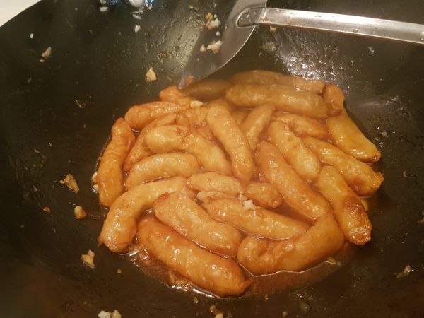 中火煎甜不辣煎到膨脹微焦黃，
為了健康不用油炒方式所以用油稍微放多些以煎的方式達成，
接著下入蒜末拌炒煸香，
再來就醬調好的醬料下入拌勻，
大火收汁。