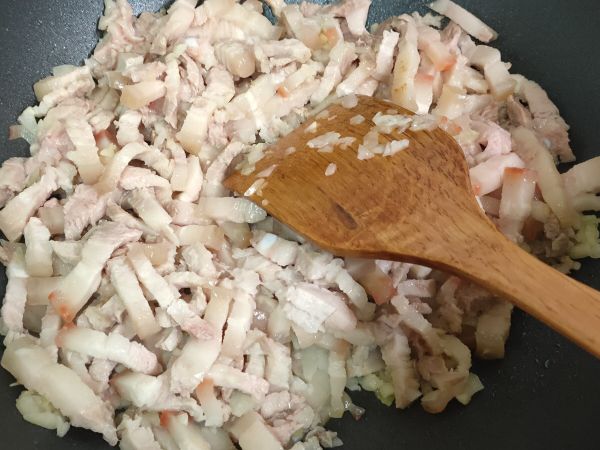 油鍋炒香蒜末，再加入洋蔥末炒香，最後加入三層肉條炒到三層肉逼出油