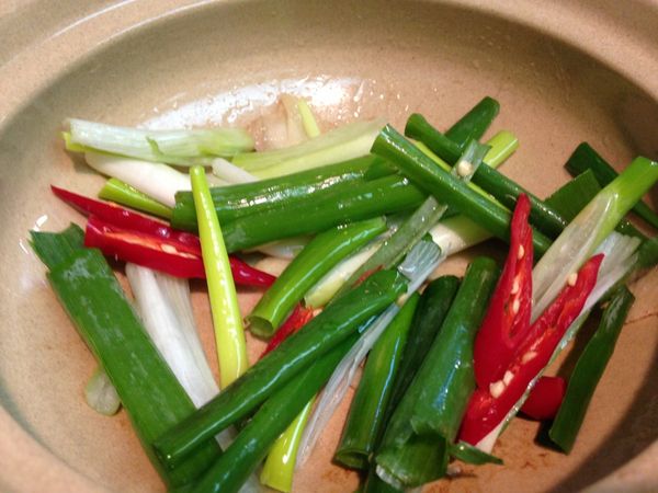 取一只砂鍋，將步驟2鍋底剩下的油倒入，小火依序把薑片、蔥段、辣椒下鍋拌炒出香氣。