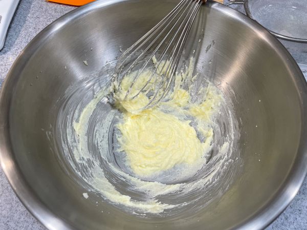 在軟化的奶油裡分2-3次加入糖，攪拌至奶油變成偏白色