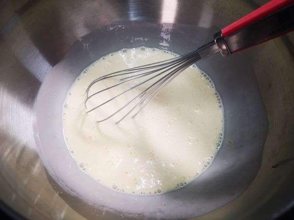 倒入動物性鮮奶油(180g)與鮮奶(90g)，繼續攪拌混合