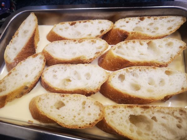 將法國麵包切成每片約2.5cm的尺寸，放入倒有混和蛋液的不鏽鋼備料方盆中，先將每面都沾上混和蛋液後，排列好蓋上保鮮膜，送至冰箱存放，並每60分鐘翻面一次，需翻3次 (浸泡180分鐘)