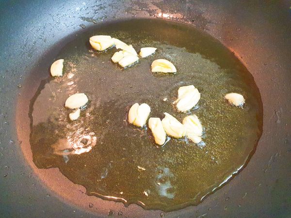 轉中火/先放入蒜頭/炒至變色。